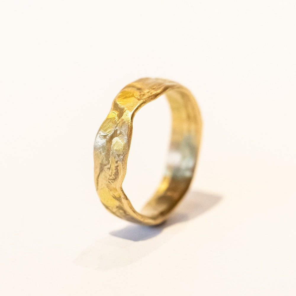 An organic textured yellow gold wide wedding band.