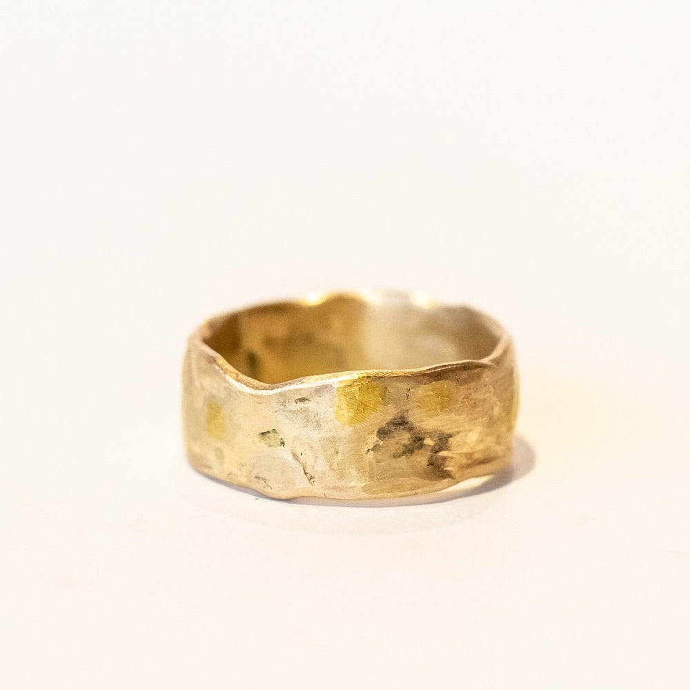 An organic textured wide yellow gold wedding band.