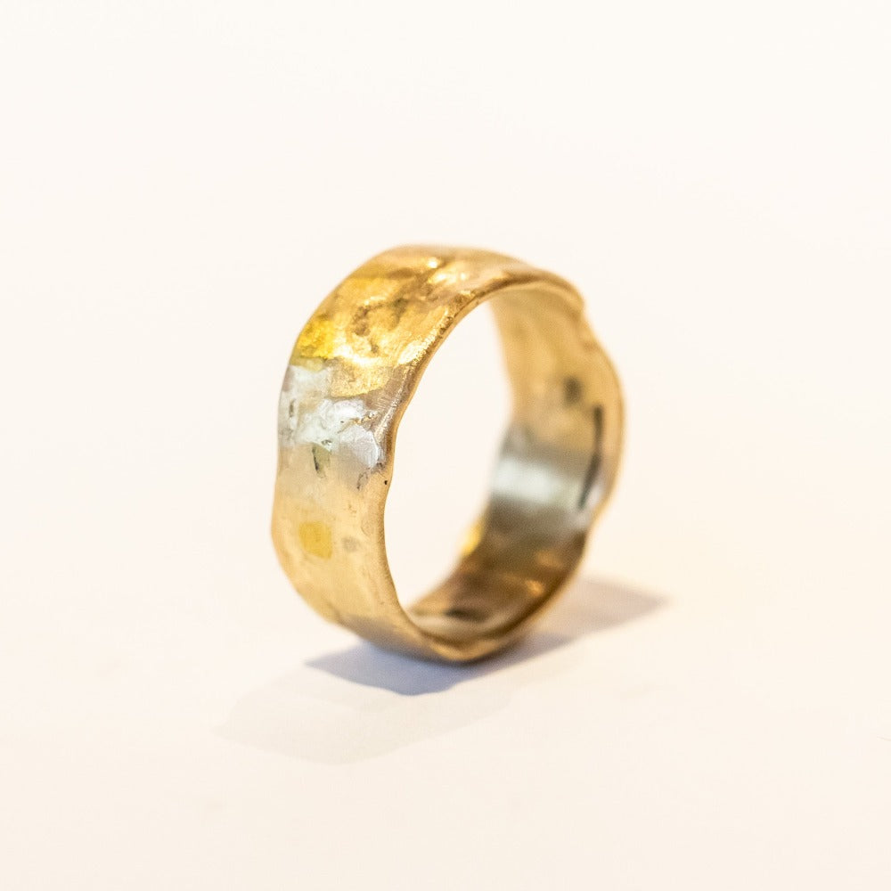 An organic textured wide yellow gold wedding band.