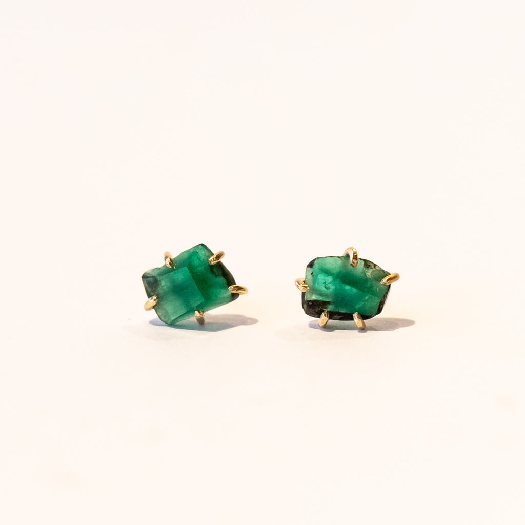 Rough faceted green emerald stud earrings in yellow gold.