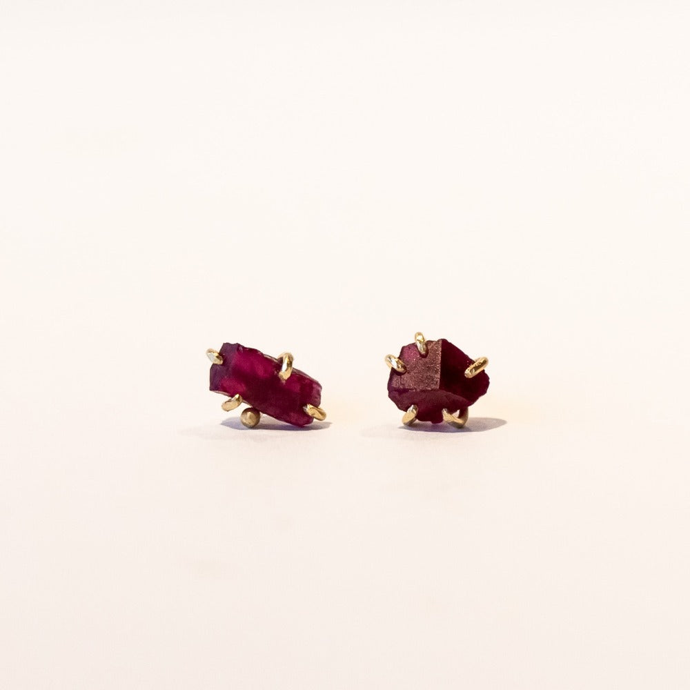 Small, asymmetrical rough faceted ruby stud earrings in yellow gold.
