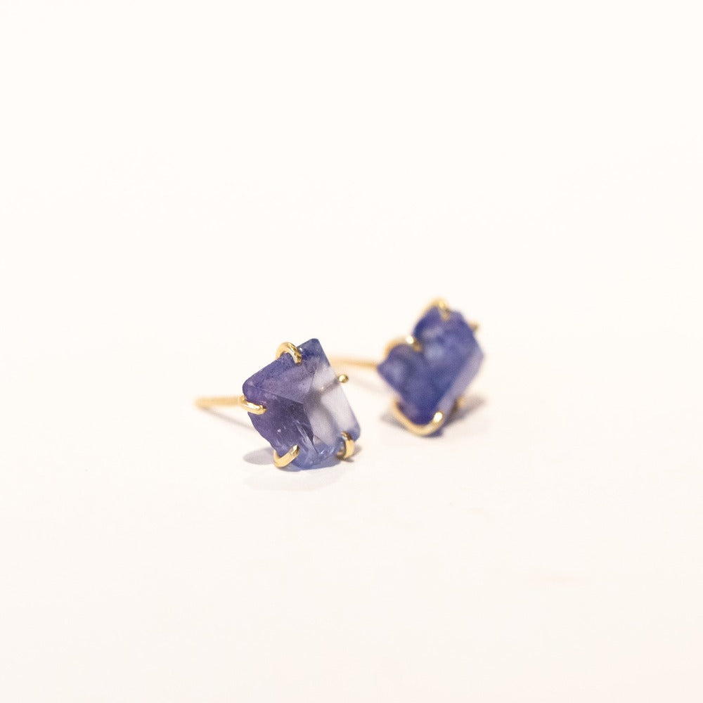 Asymmetrical, rough faceted tanzanite stud earrings in yellow gold.