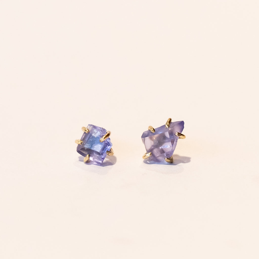 Asymmetrical, rough faceted tanzanite stud earrings in yellow gold.