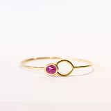 A yellow gold wire bracelet set with a bezel set ruby at one end that fits through a loop at the other.