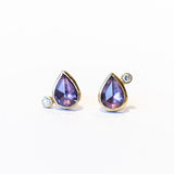 Pear shape purple sapphire stud earrings bezel set in yellow gold and accented by tiny round diamonds.
