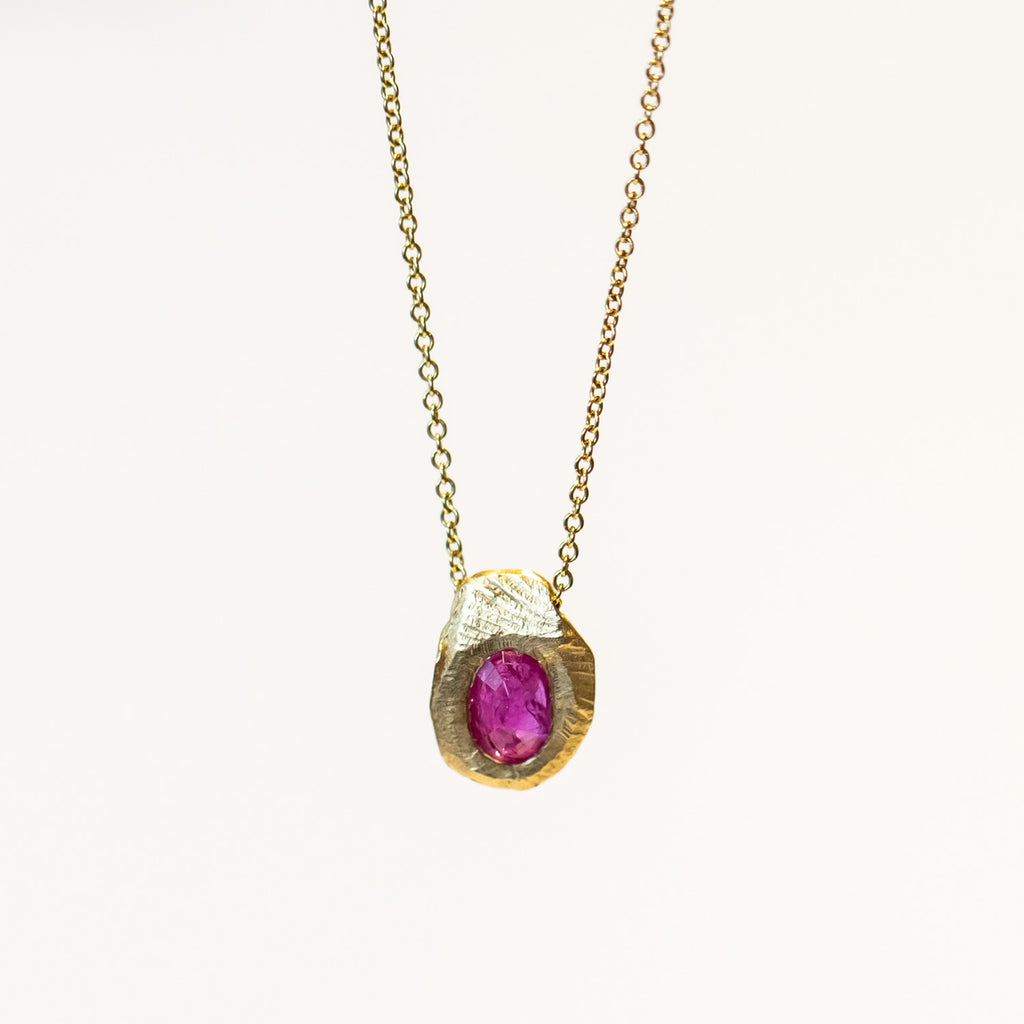 On oval ruby set into a carved yellow gold slider pendant on a classic cable chain necklace.