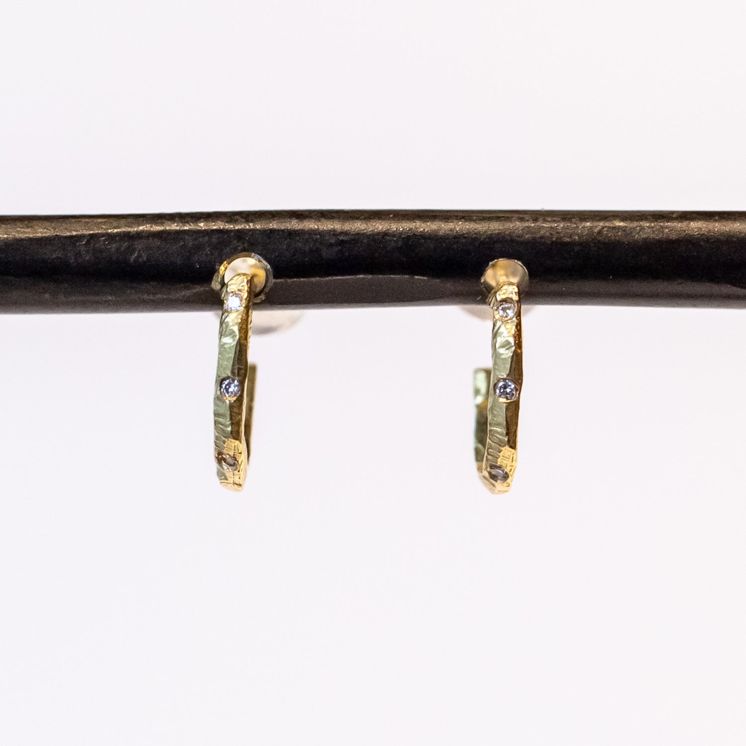 Small, textured yellow gold hoop earrings with three small diamonds along the front.