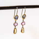 A pair of drop earrings featuring different colored freeform cut sapphires set in different ways in yellow gold.