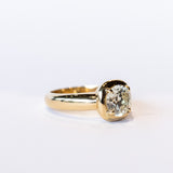 A chunky gold solitaire engagement ring featuring an old mine European cut diamond prong set into a cushion-like setting.