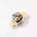 A chunky gold solitaire engagement ring featuring an old mine European cut diamond prong set into a cushion-like setting.
