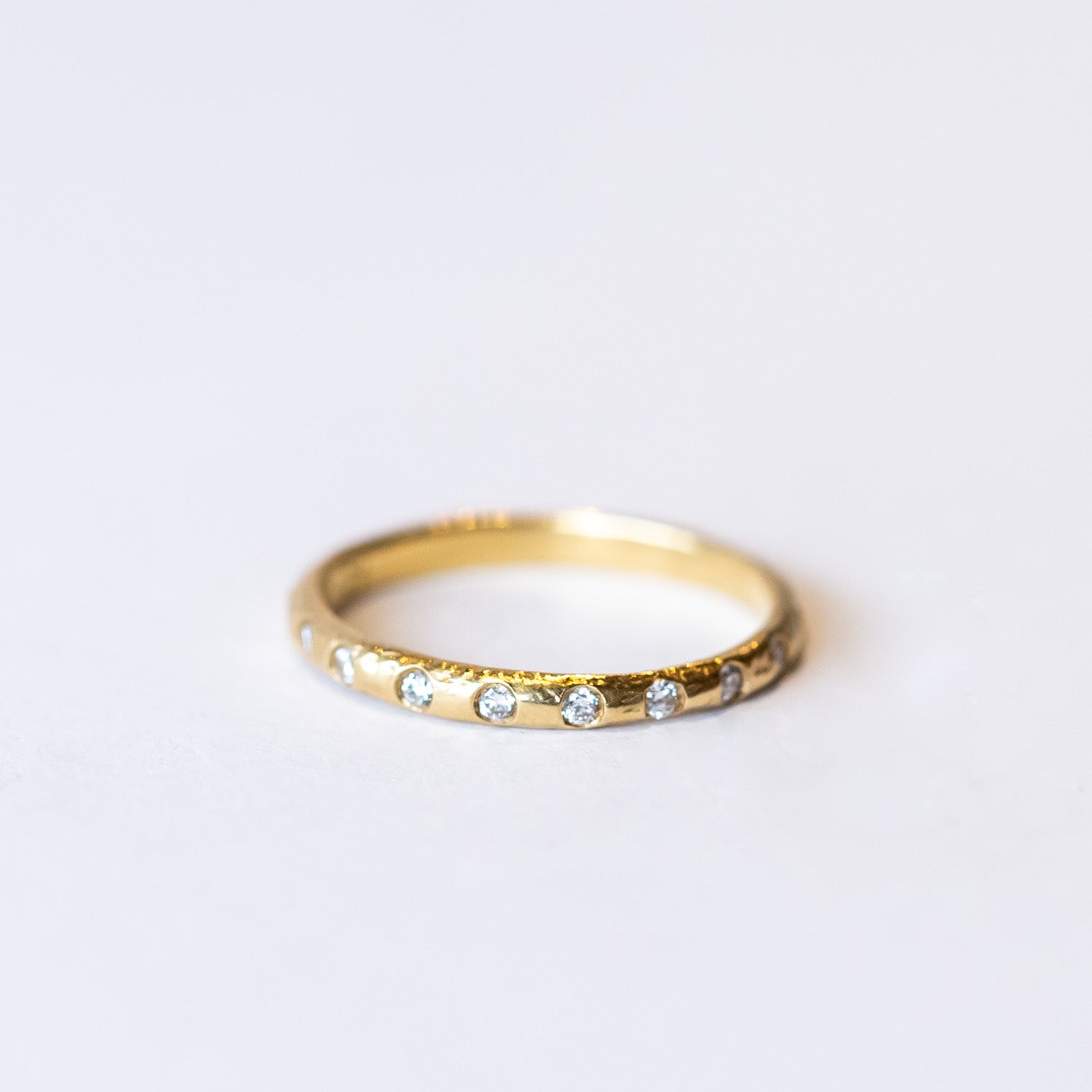 A textured yellow gold wedding band with flush set diamonds all the way around.