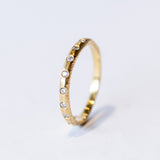 A textured yellow gold wedding band with flush set diamonds all the way around.