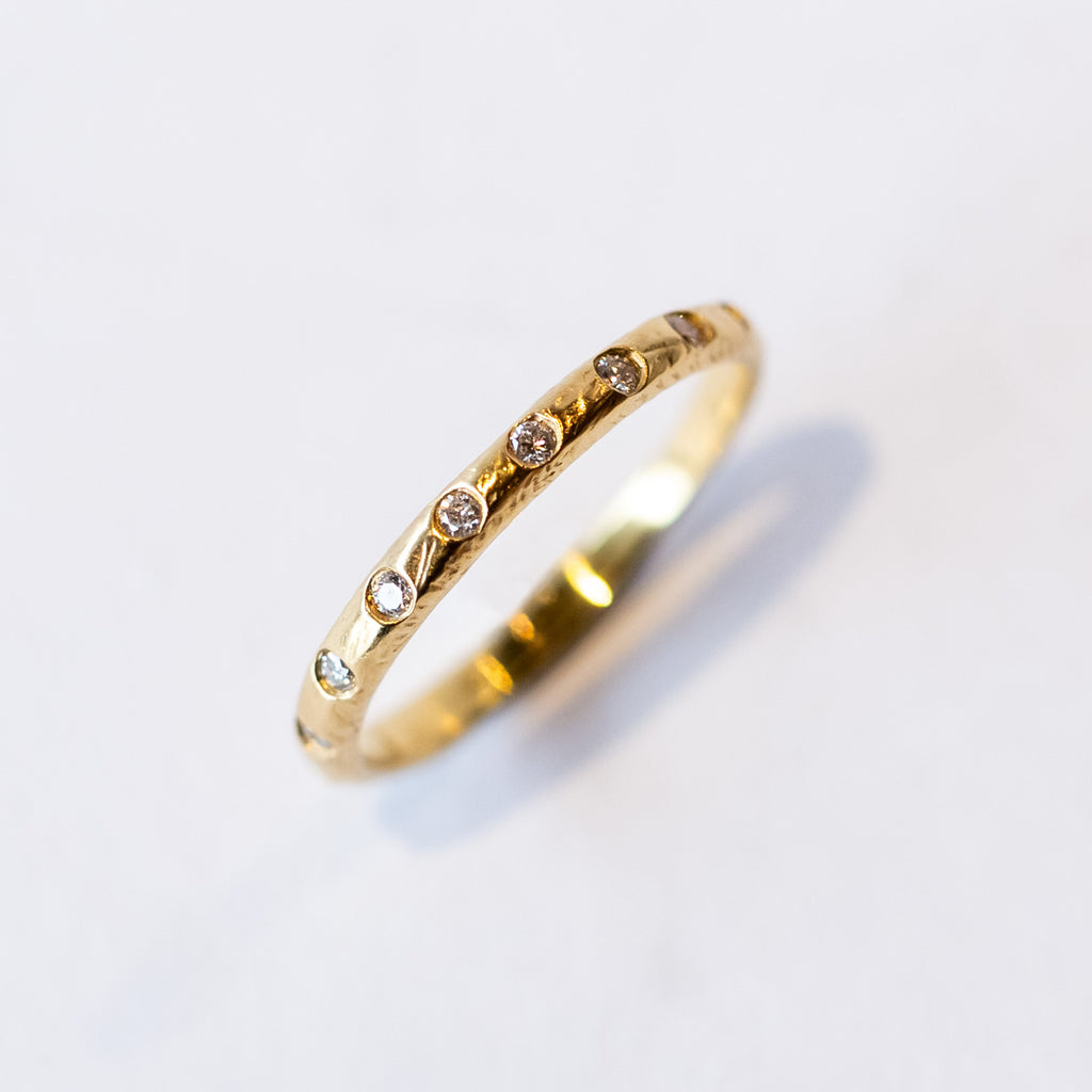 A textured yellow gold wedding band with flush set diamonds all the way around.