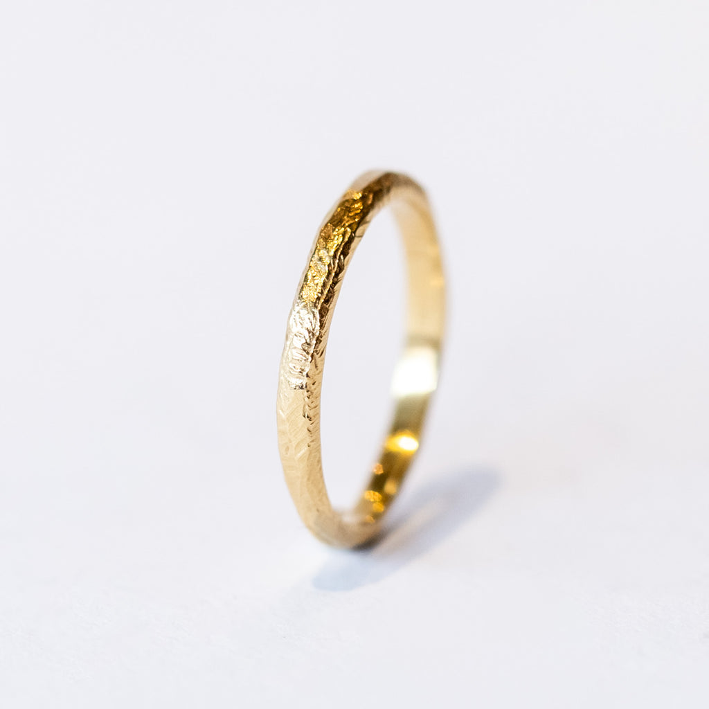 A carved-texture, slim yellow gold band.