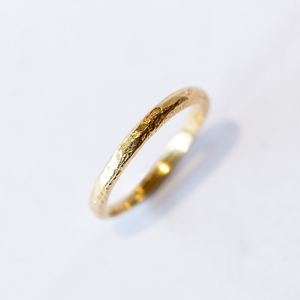 A carved-texture, slim yellow gold band.