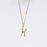 A snake forms the letter K in this gold initial pendant hung from a classic cable chain.