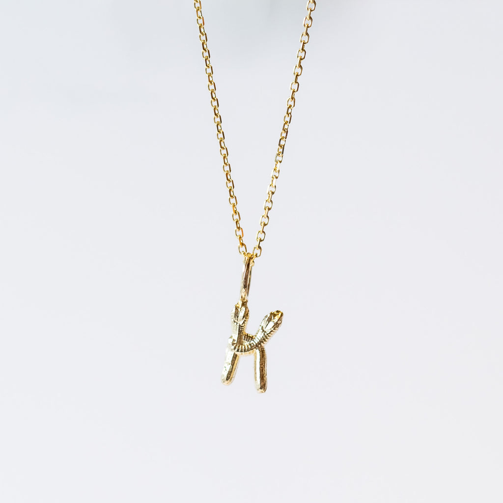 A snake forms the letter K in this gold initial pendant hung from a classic cable chain.