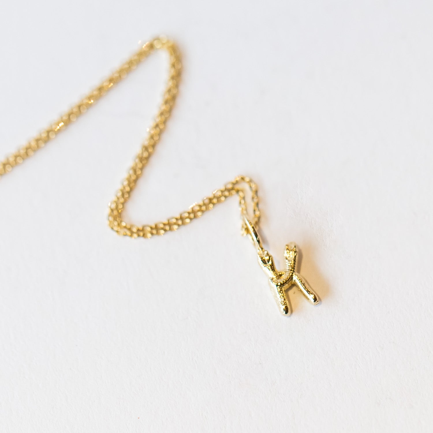 A snake forms the letter K in this gold initial pendant hung from a classic cable chain.
