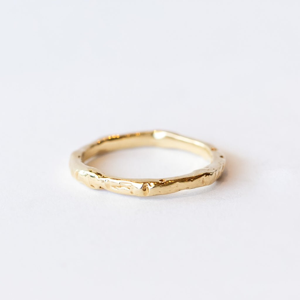 A slender yellow gold wedding band with hand carved texture.