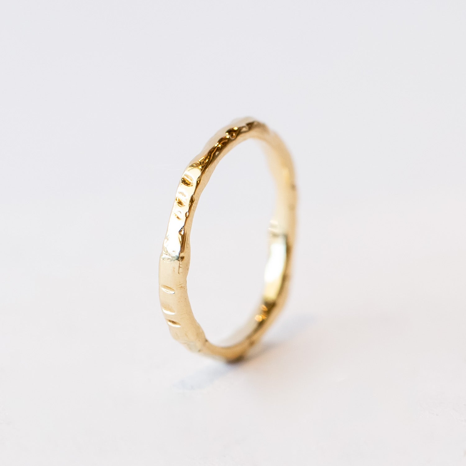 A slender yellow gold wedding band with hand carved texture.