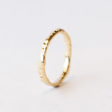 A slender yellow gold wedding band with hand carved texture.