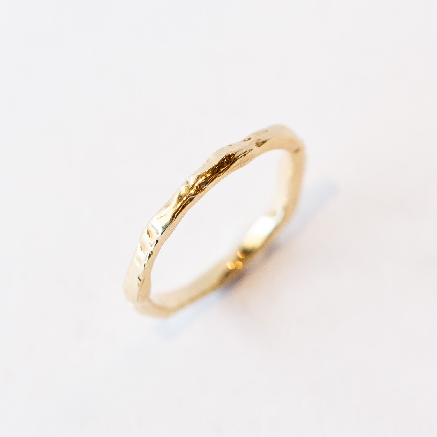 A slender yellow gold wedding band with hand carved texture.