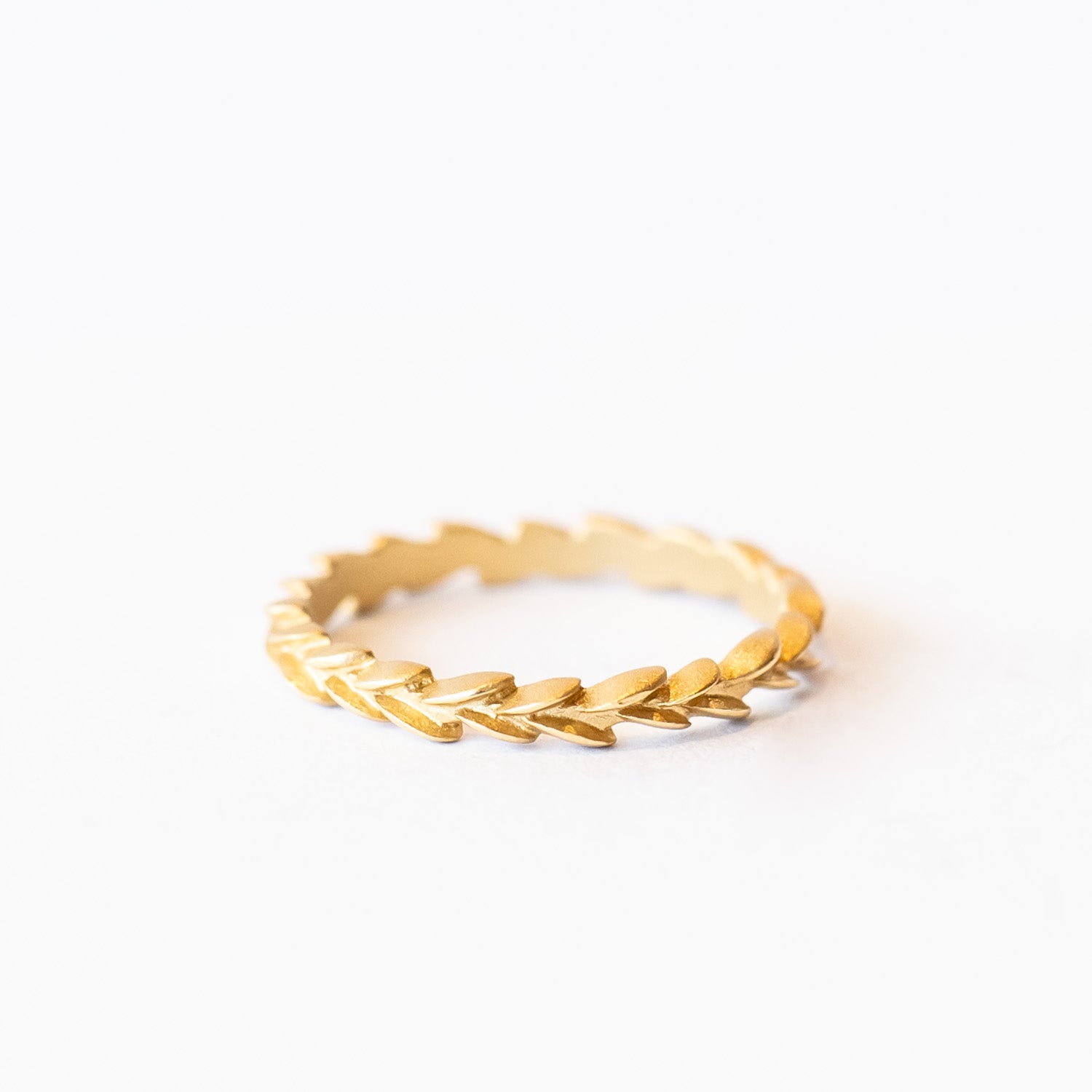A carved laurel leaf pattern yellow gold wedding band.