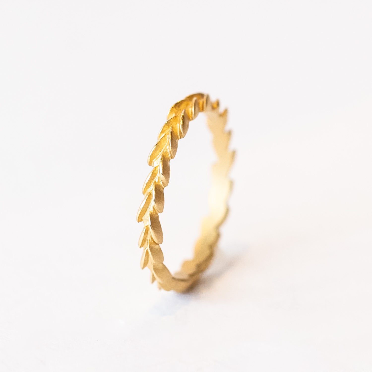 A carved laurel leaf pattern yellow gold wedding band.