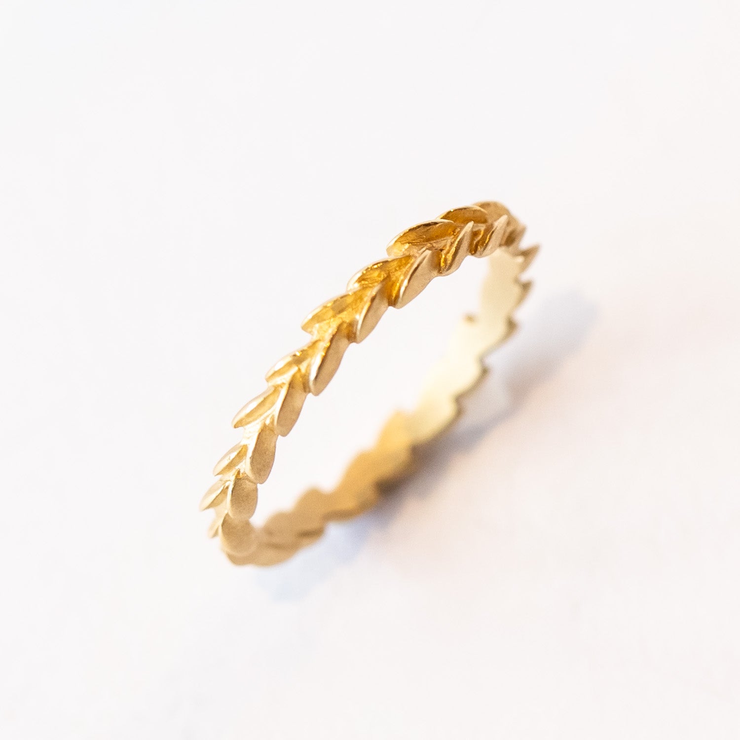 A carved laurel leaf pattern yellow gold wedding band.