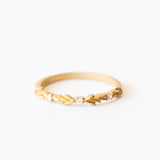 A lauren-wreath patterned wedding band in yellow gold with three accent diamonds.