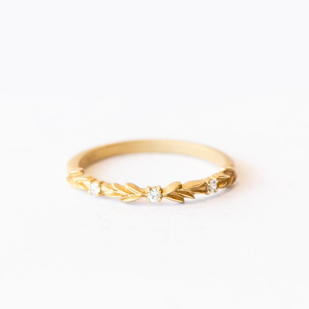 A lauren-wreath patterned wedding band in yellow gold with three accent diamonds.
