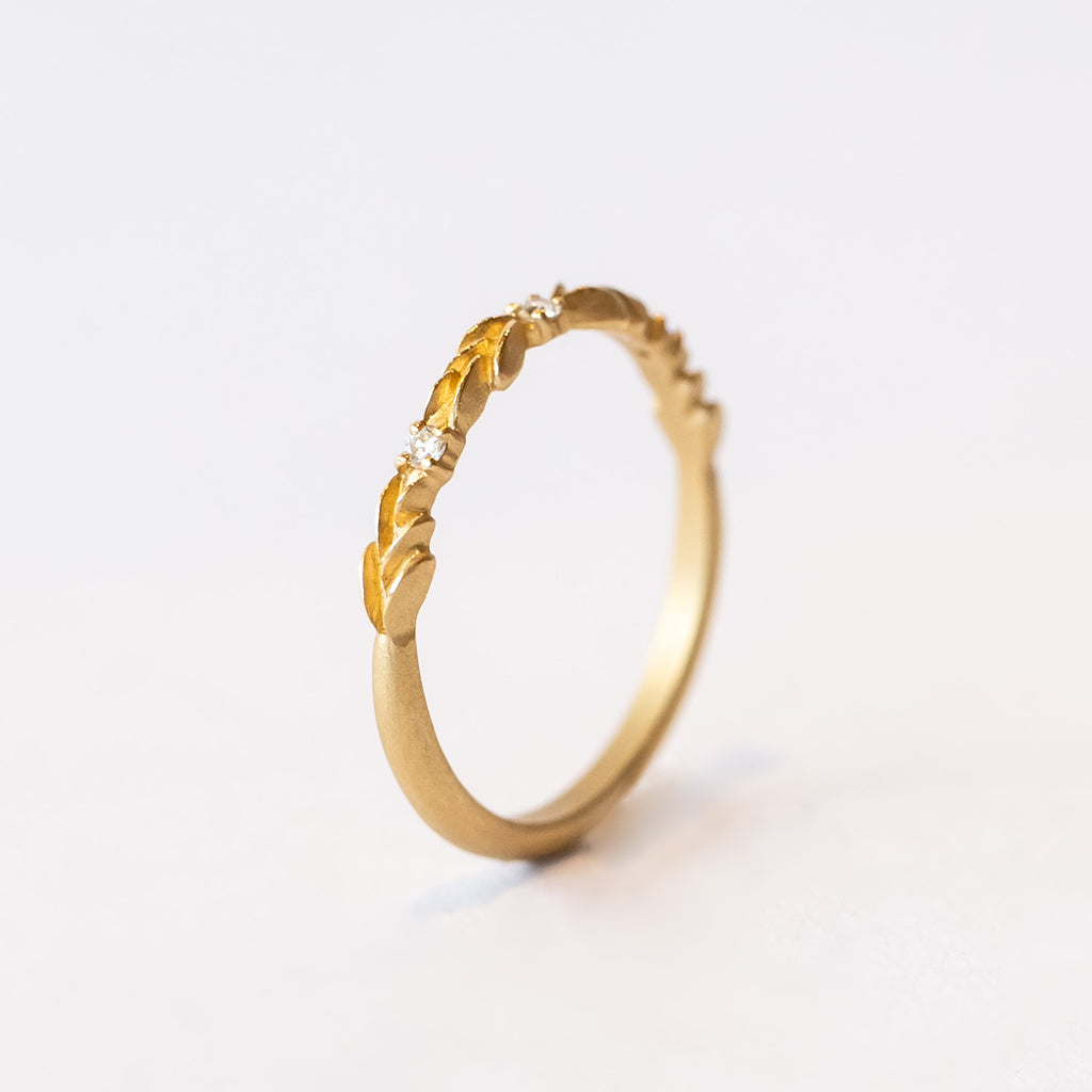 A lauren-wreath patterned wedding band in yellow gold with three accent diamonds.