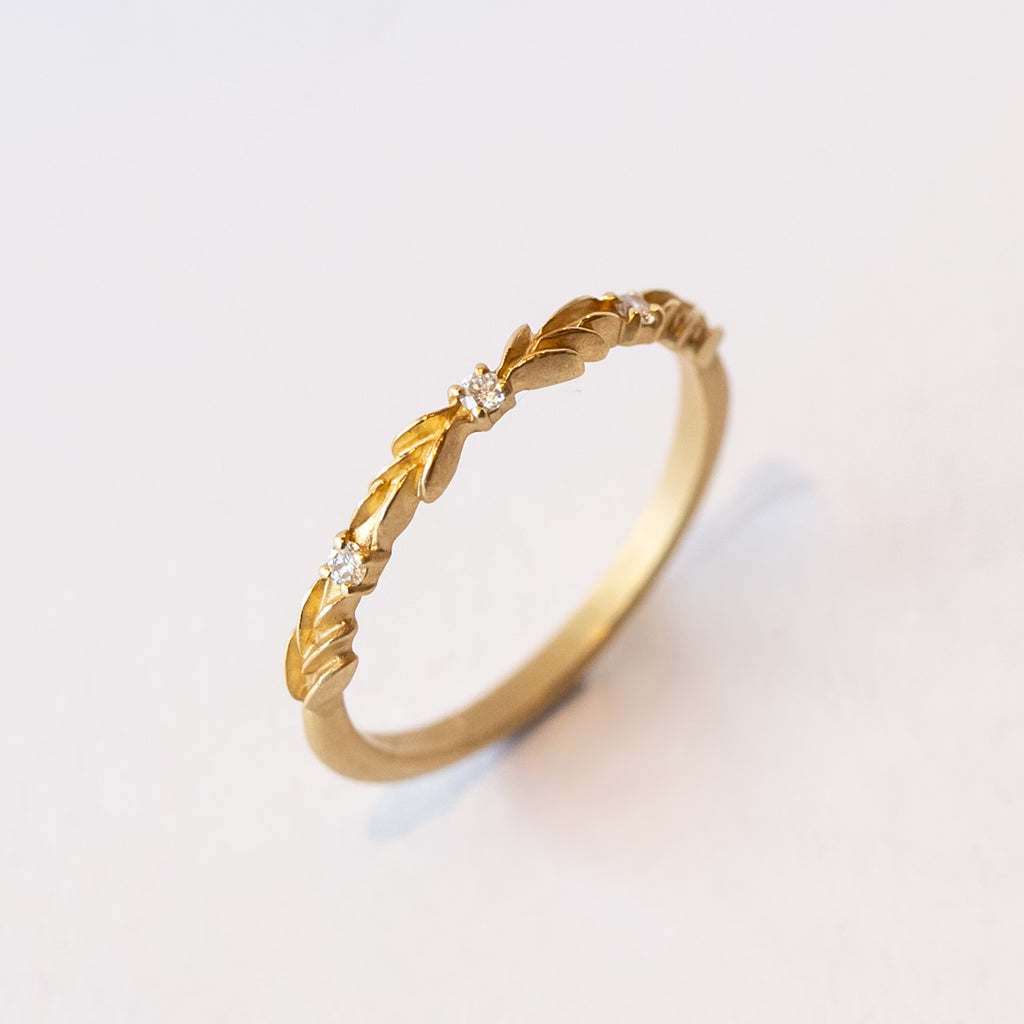 A lauren-wreath patterned wedding band in yellow gold with three accent diamonds.