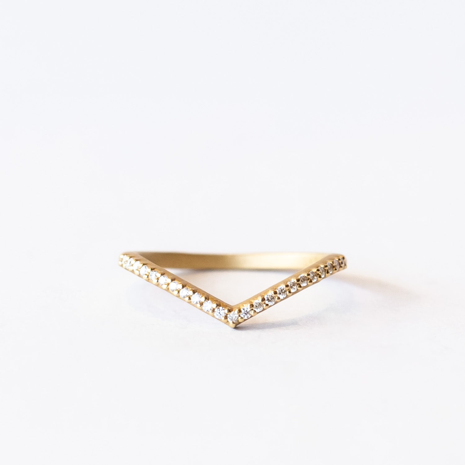 A yellow gold pointed contour wedding band set with a single row of tiny pave diamonds.