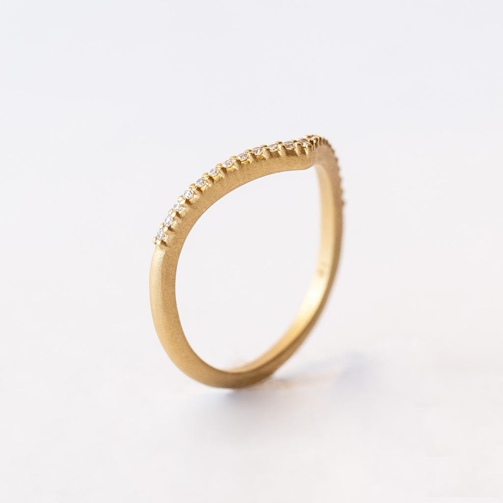 A yellow gold pointed contour wedding band set with a single row of tiny pave diamonds.