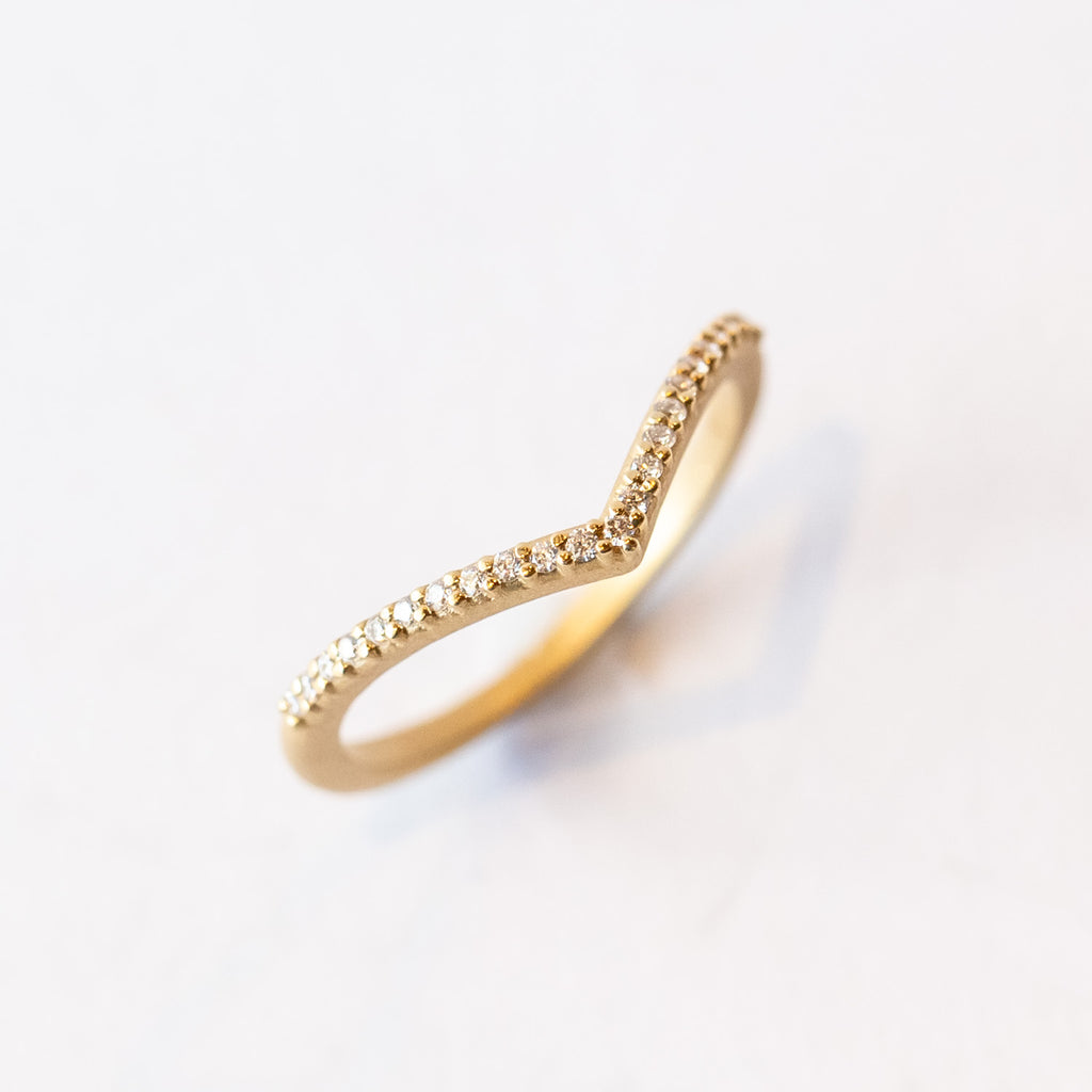 A yellow gold pointed contour wedding band set with a single row of tiny pave diamonds.