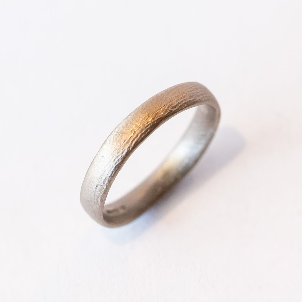 A contemporary men's wedding band with rounded edge in a lightly textured matte finish.