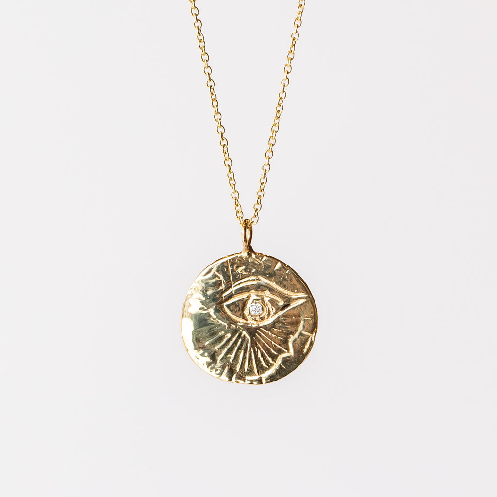 Carved yellow gold medallion necklace with an eye, a diamond at its center, from Communion by Joy.