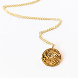 Carved yellow gold medallion necklace with an eye, a diamond at its center, from Communion by Joy.