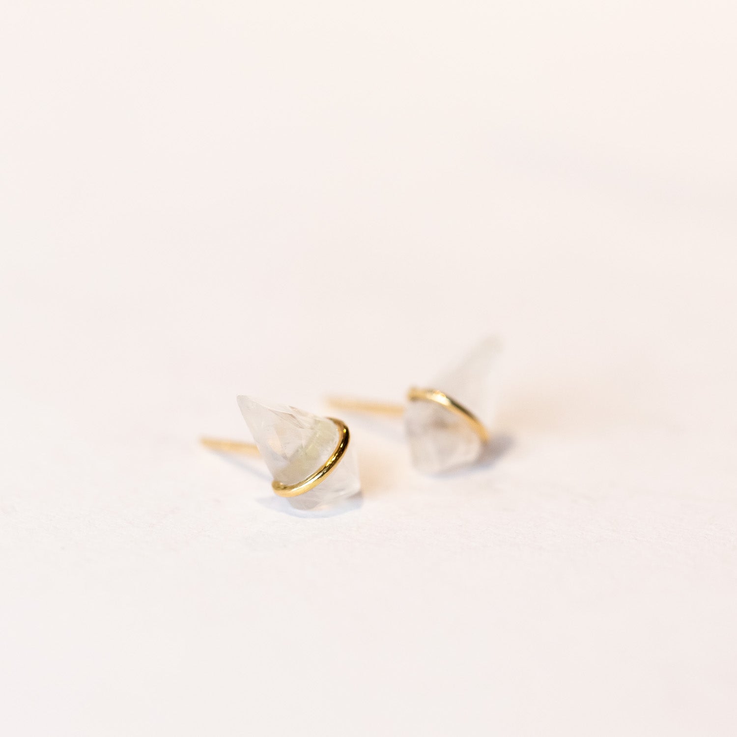 Stud earrings featuring kite-shaped moonstone gems wrapped in a band of yellow gold.