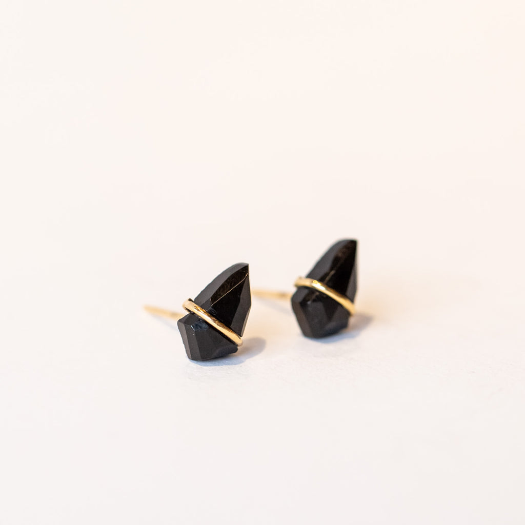 Stud earrings featuring kite-shaped black onyx stones wrapped in a slender band of yellow gold.