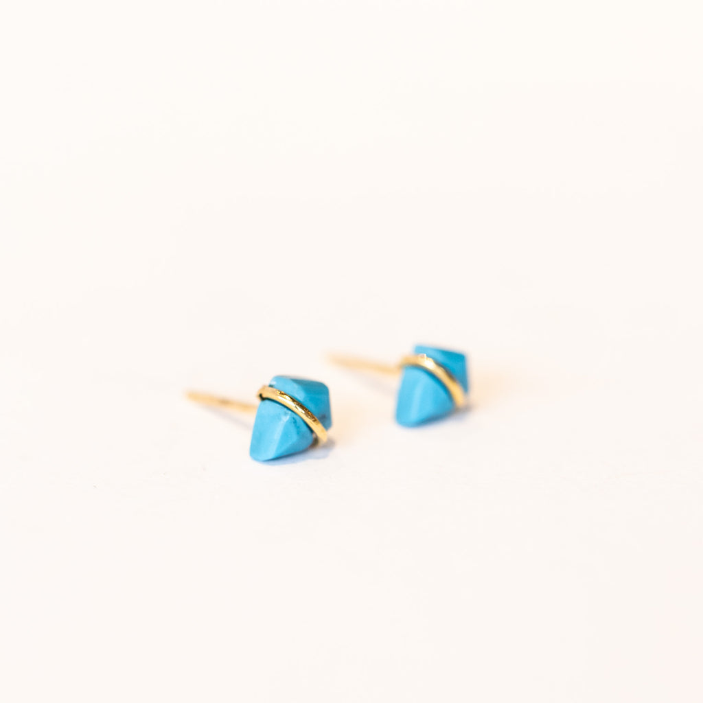 Stud earrings featuring petite, kite-shaped turquoise gemstones wrapped in a slim band of yellow gold.