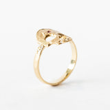 A hand carved gold ring with a skull shaped top, set with diamond teeth and a ruby on the forehead.