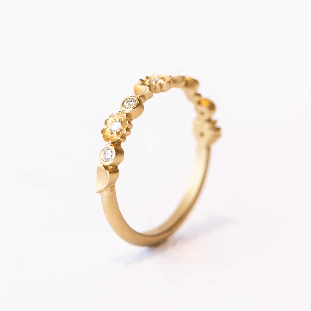 A floral motif diamond wedding band in yellow gold.