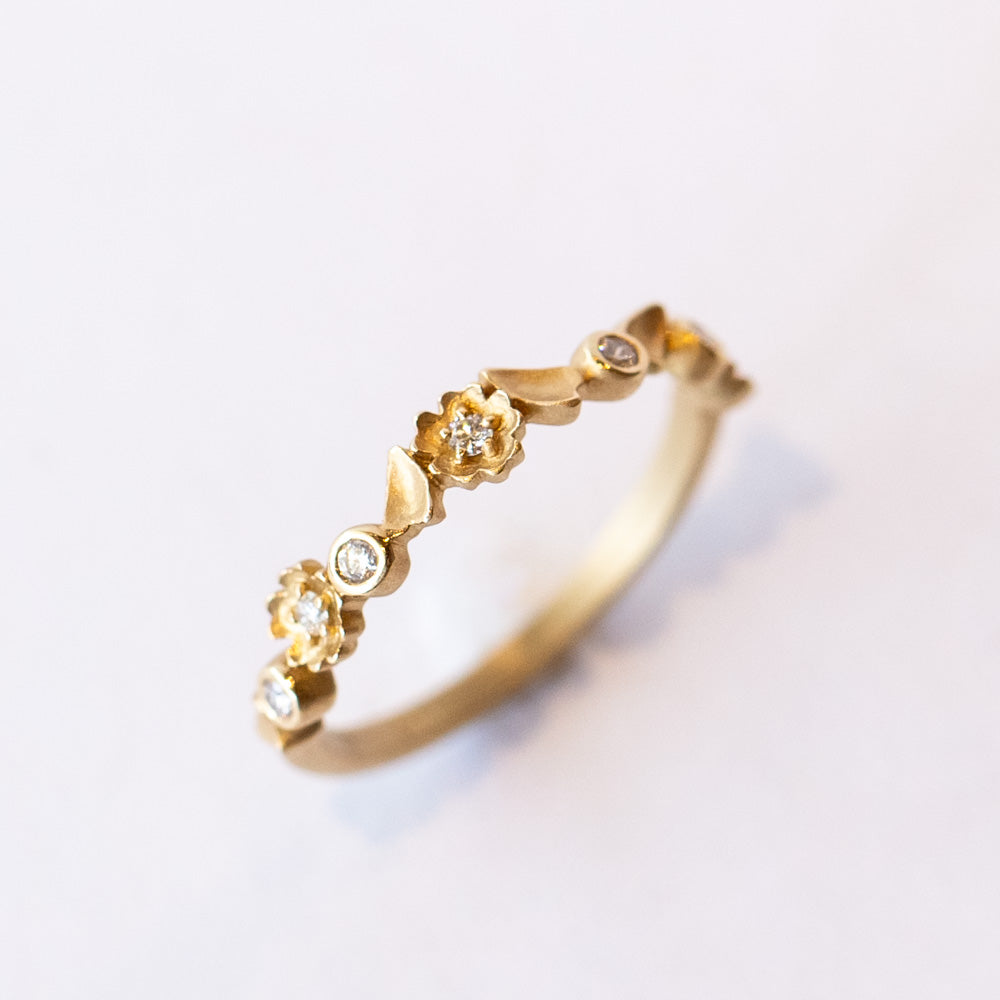 A floral motif diamond wedding band in yellow gold.