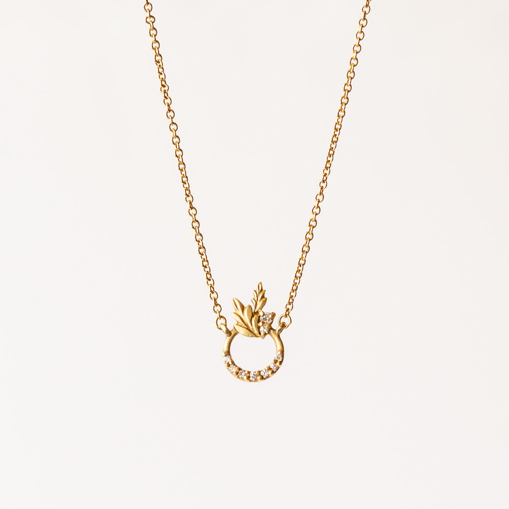 A doorknocker-style diamond accented station necklace featuring a little leaf design on a yellow gold chain.