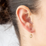 Yellow gold drop earrings with oval blue sapphires set in textured bezels. On model.