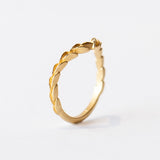 A yellow gold, matte finished contour wedding band that comes to a point, adorned with carved laurel pattern on the top.