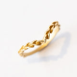 A yellow gold, matte finished contour wedding band that comes to a point, adorned with carved laurel pattern on the top.