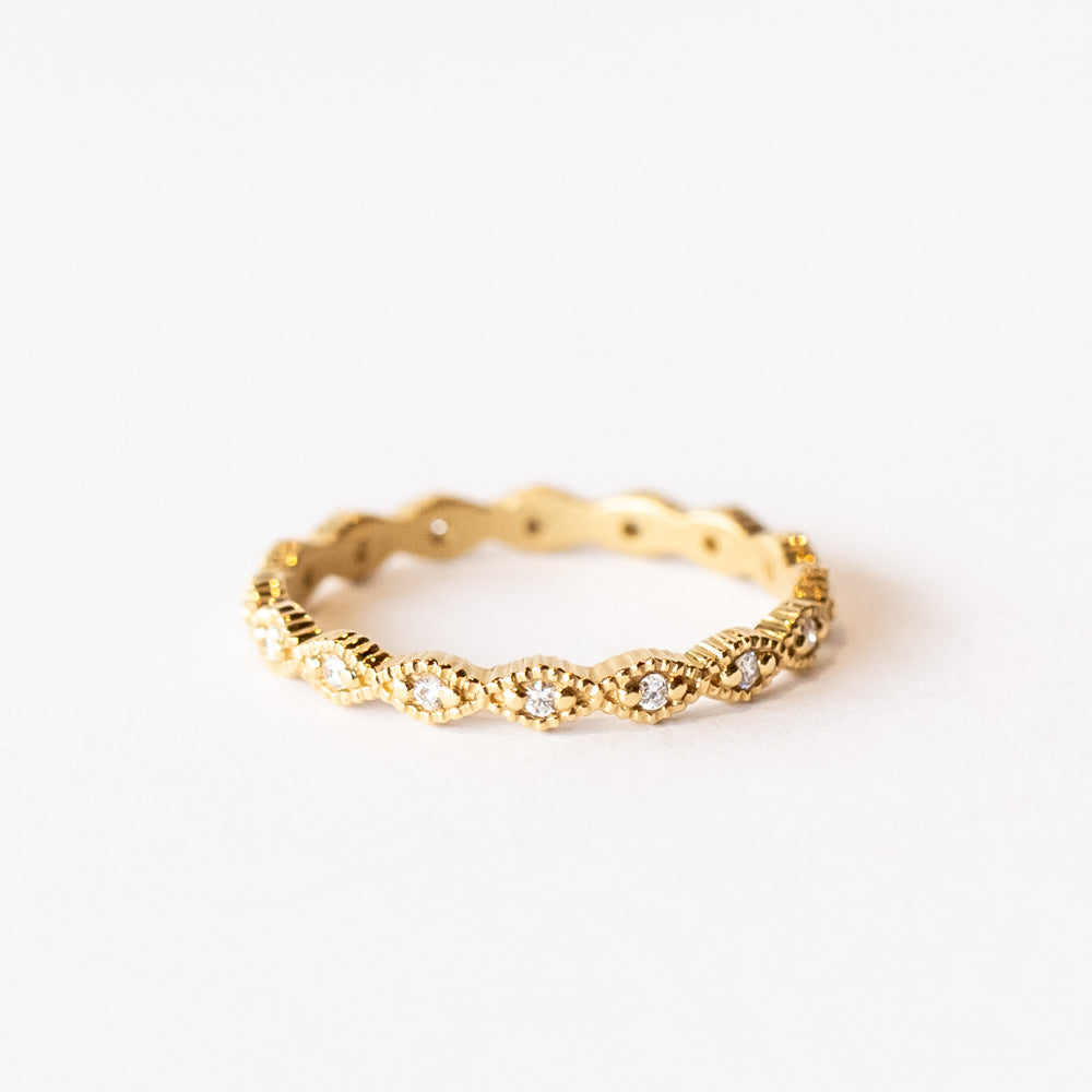 A yellow gold diamond eternity band with diamond shaped pattern all the way around, each shape is set with a small round diamond with milgrain bead edges.